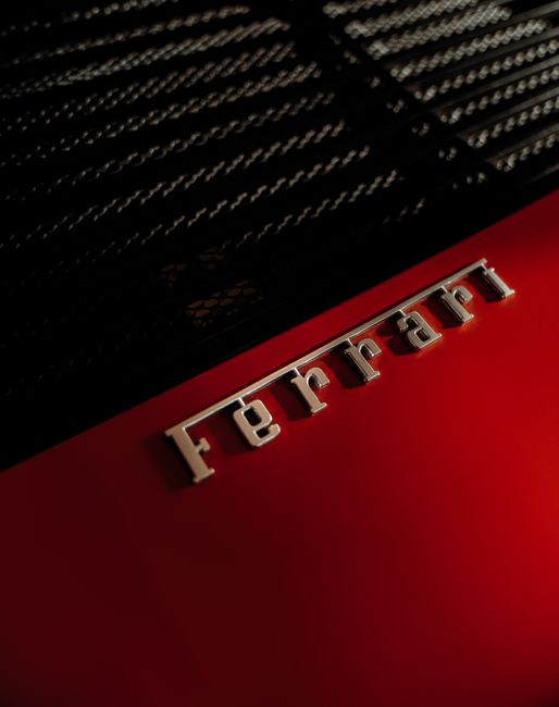A close-up view of the Ferrari emblem on a sleek red car, showcasing luxury and design.