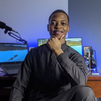 Handsome man in a modern home office posing with a confident expression, dressed in a stylish black outfit.