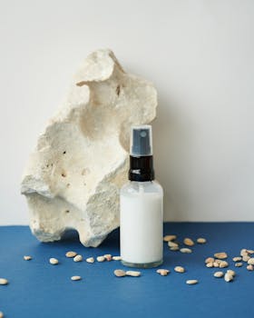 Sophisticated product shot featuring a cosmetic spray bottle with a natural rock backdrop and scattered pebbles.