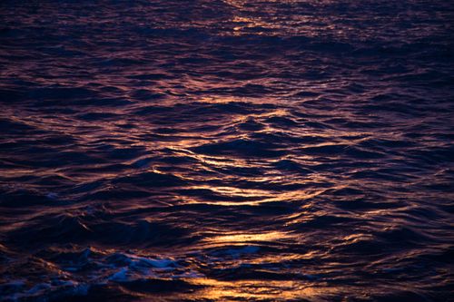 Free Calm ocean waves reflecting the warm, golden sunset in Cartagena, Spain. Stock Photo
