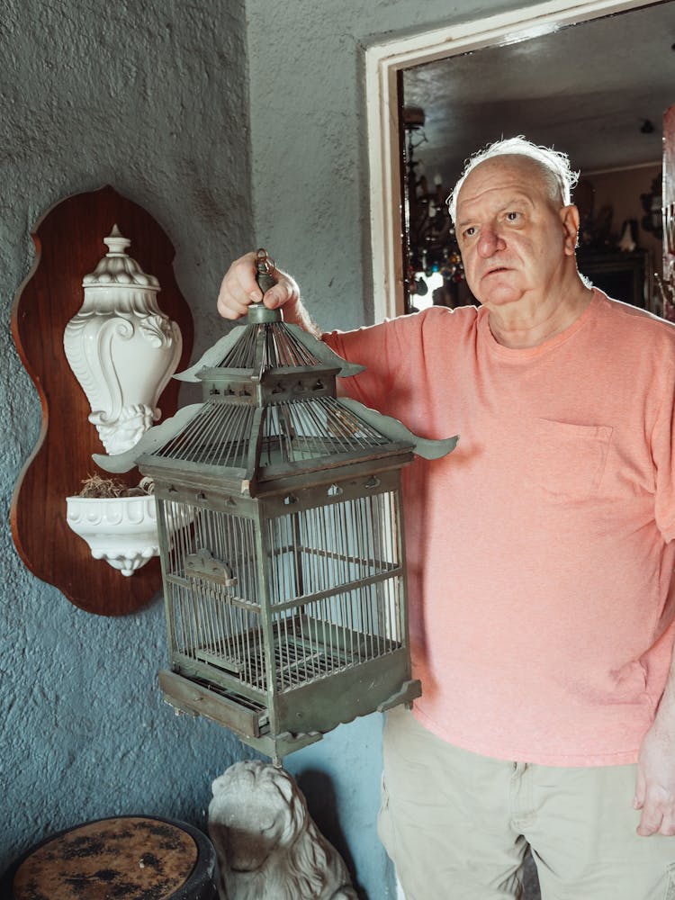 An Elderly Man Carrying A Birdcage