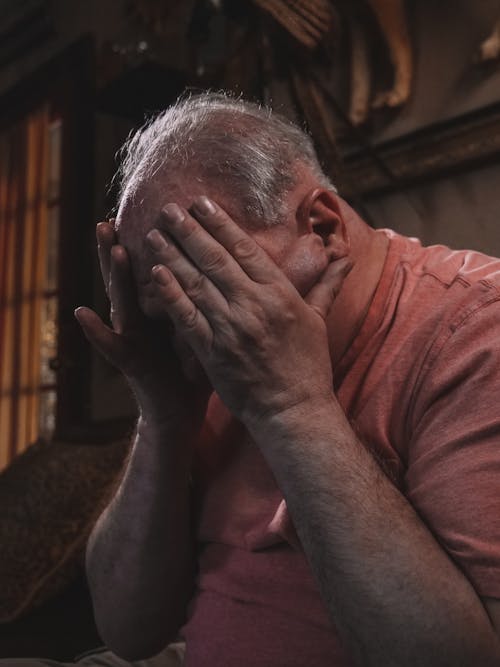 Free An Elderly Man with His Hands on His Face Stock Photo