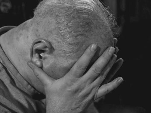 A Close-up Shot of an Elderly Man Covering His Face
