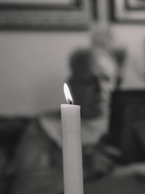 Free A grayscale image of a candle flame casting a soft glow in a serene and moody atmosphere. Stock Photo