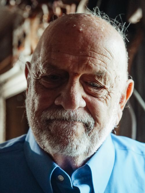 Free Close-up of an elderly man with a beard, wearing a blue shirt, with a thoughtful expression and wrinkles visible. Stock Photo