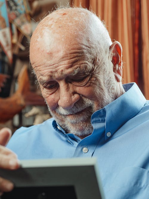 Free Man in Blue Button Down Shirt Looking at a Picture Stock Photo