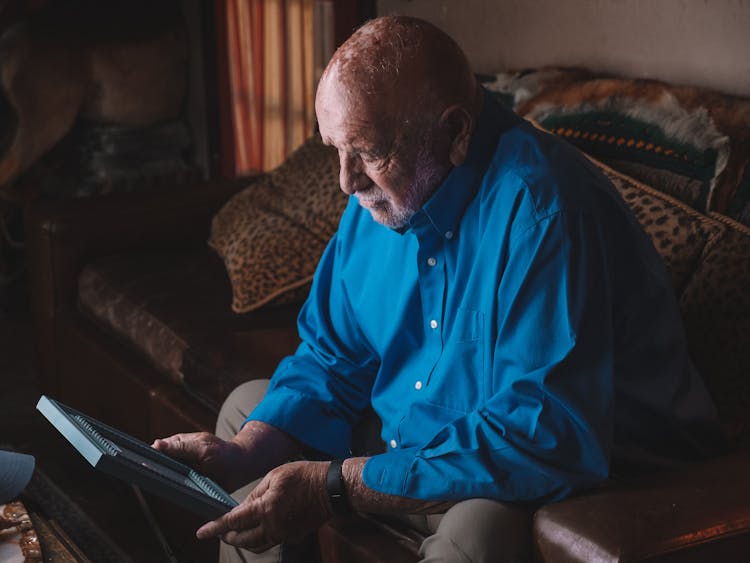 Man Sitting On A Sofa Holding A Photo Frame