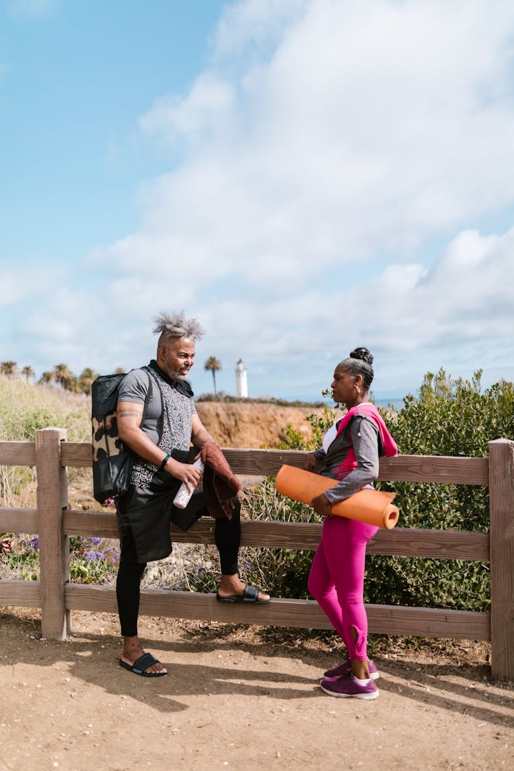 A Man And Woman Talking Beside A Wooden Fence