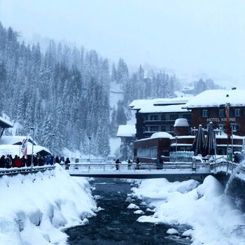 阿尔卑斯山小镇的冬日风景如画，有一座桥梁、白雪皑皑的树木和湍急的河流