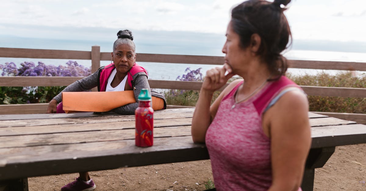 2 Women Sitting on Bench Holding Bottle