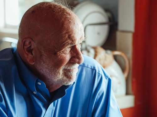 Free Portrait of a senior man wearing a blue shirt and beard, captured in a cozy indoor setting. Stock Photo