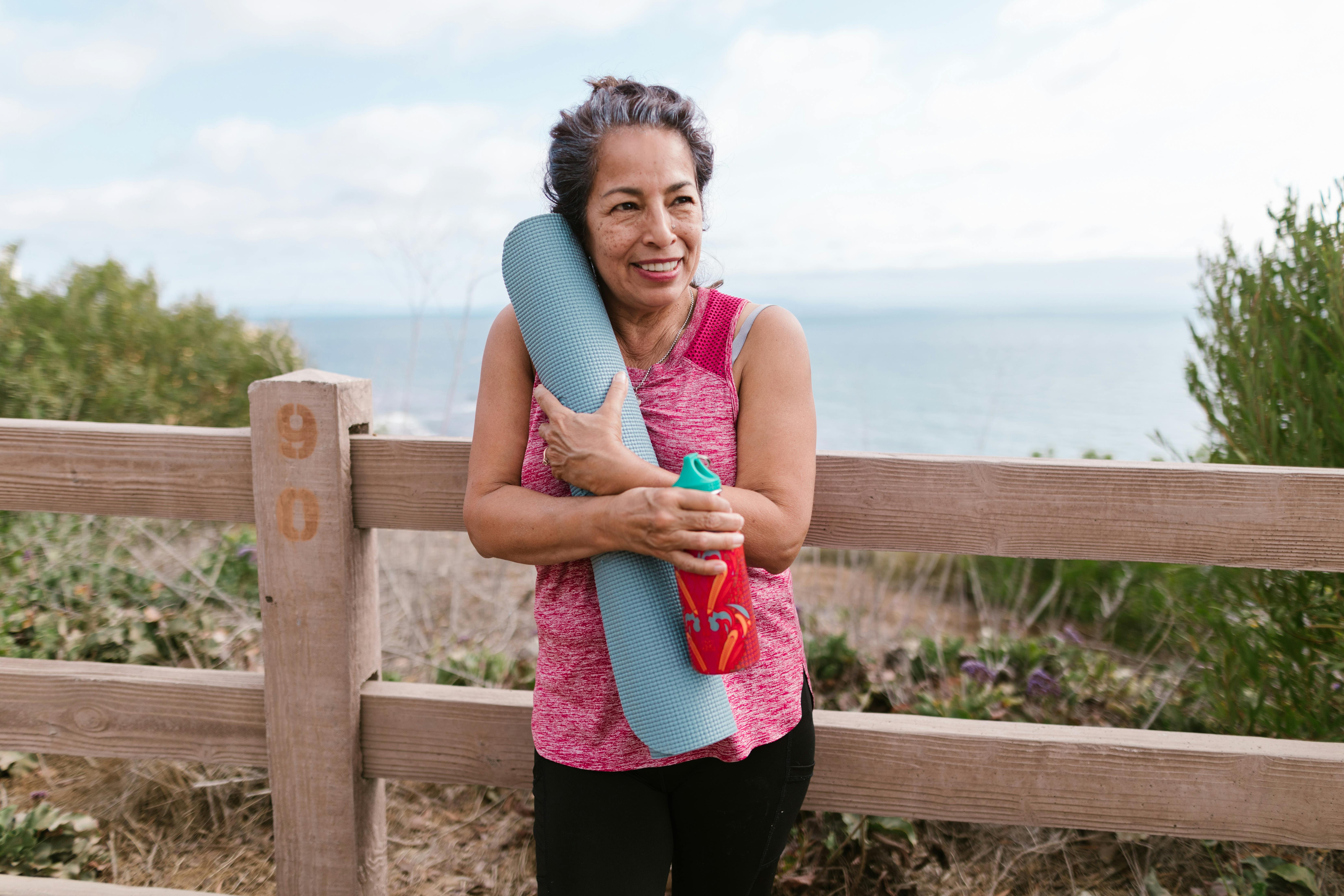 senior woman standing beside a wooden fence