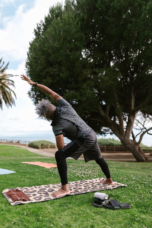 A Man Standing on a Yoga Mat while Stretching His Arms