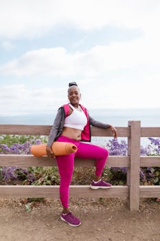 Senior woman with yoga mat posing by the seaside, promoting healthy and active lifestyle.