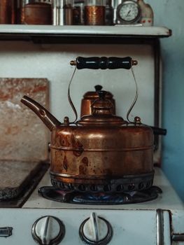 A weathered copper kettle heating on a vintage gas stove, exuding rustic charm.