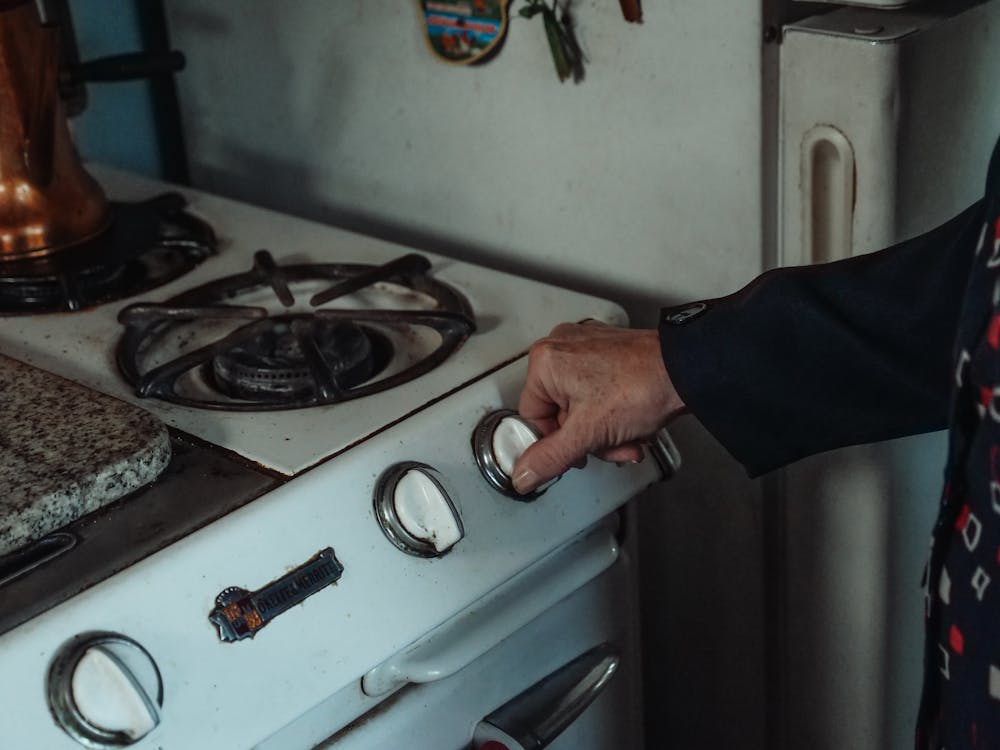 A person holding a knob on a gas stove