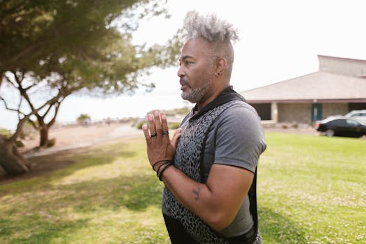 Adult man practicing meditation outdoors in a sunny park, focusing on mental wellness.