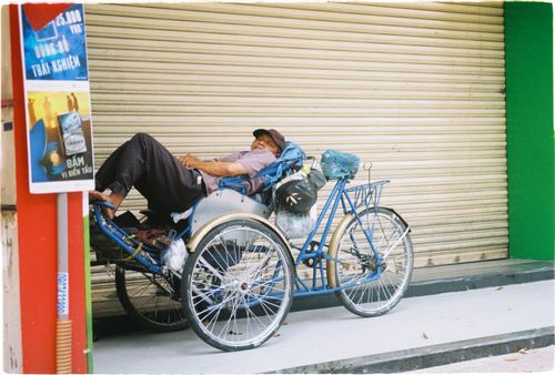 Free Pedicab driver resting on a tricycle in Ho Chi Minh City, Vietnam. Stock Photo