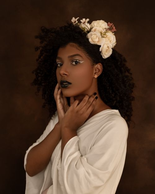 Free Beautiful portrait of a woman with curly hair and flowers, showcasing elegance and style. Stock Photo