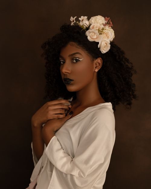 Free Elegant studio portrait of a woman with curly hair and roses in a floral headpiece. Stock Photo