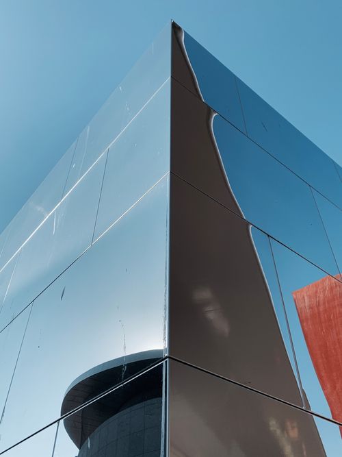 Free Low angle of a modern glass building in Amsterdam reflecting the clear blue sky. Stock Photo
