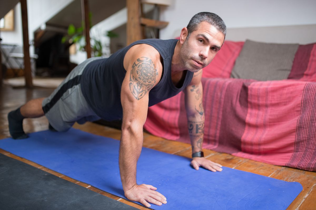 Man doing push-ups on a yoga mat at home