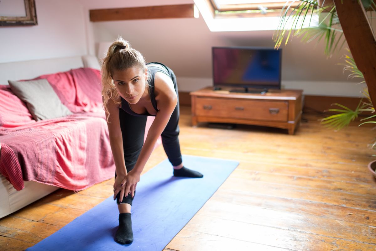Frau macht Dehnübungen auf einer Yogamatte zu Hause