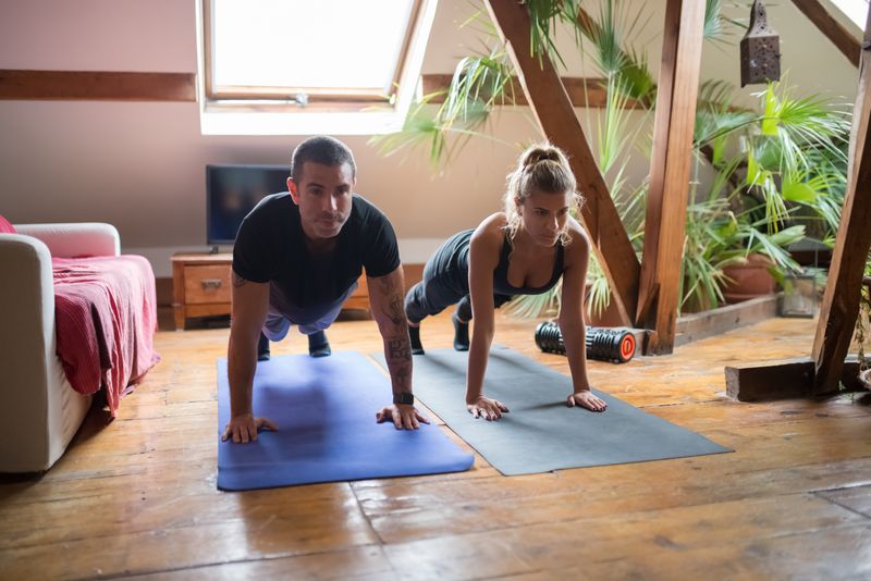 Two people doing push-ups together on yoga mats, photo by Kampus Production on Pexels