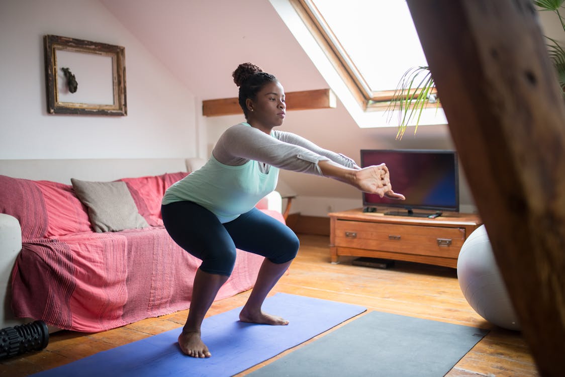A Woman Doing Squats while Stretching Her Arms
