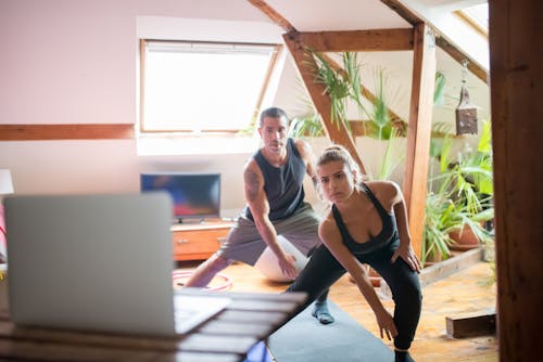 Free Man and Woman Watching on a Laptop While Working Out Stock Photo
