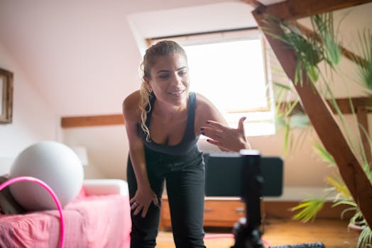 A woman energetically leads a virtual fitness class from her home, engaging with her audience online.