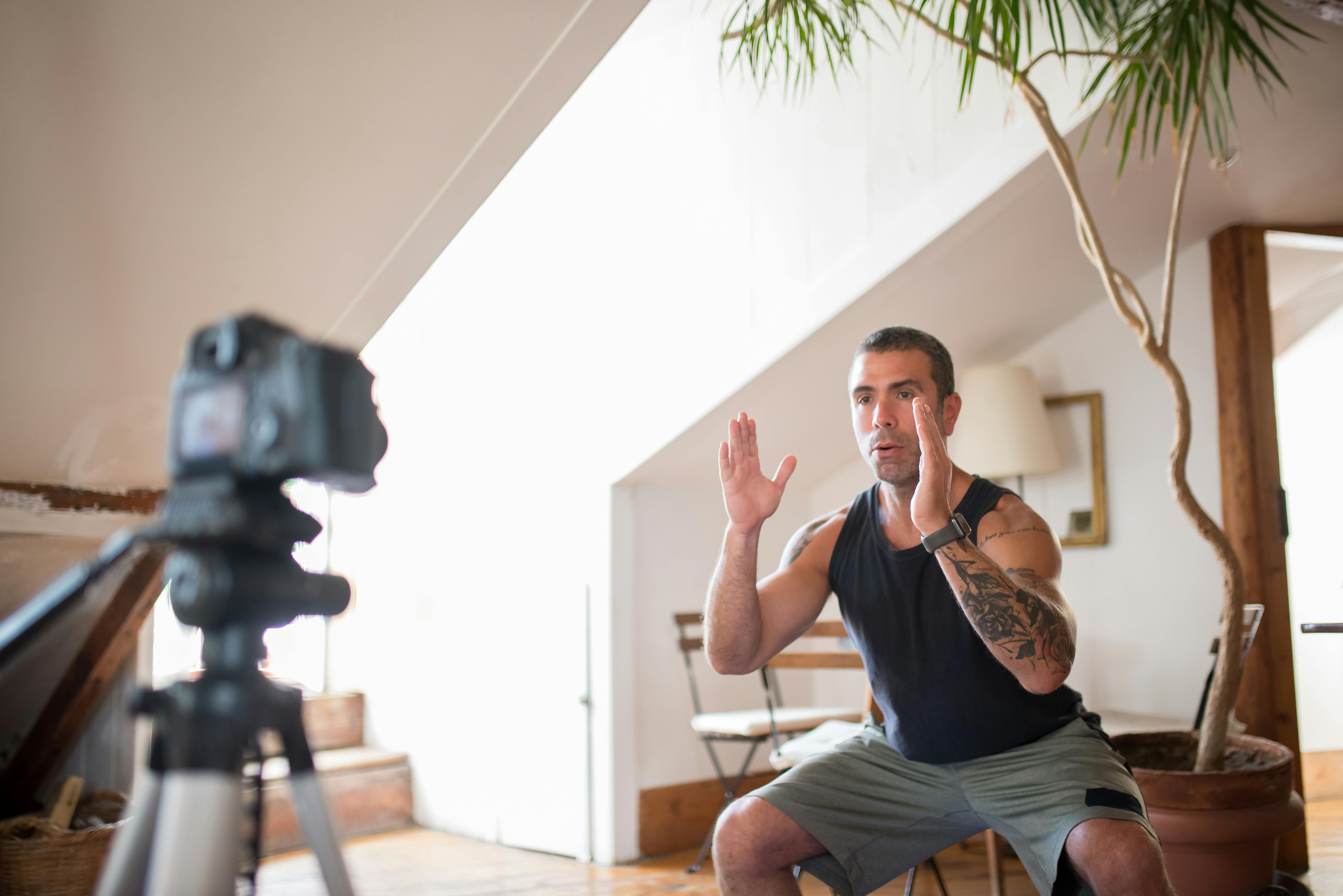 a tattooed man doing squats while facing the camera