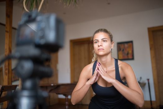 Woman conducting a fitness session at home, recorded with a DSLR camera.