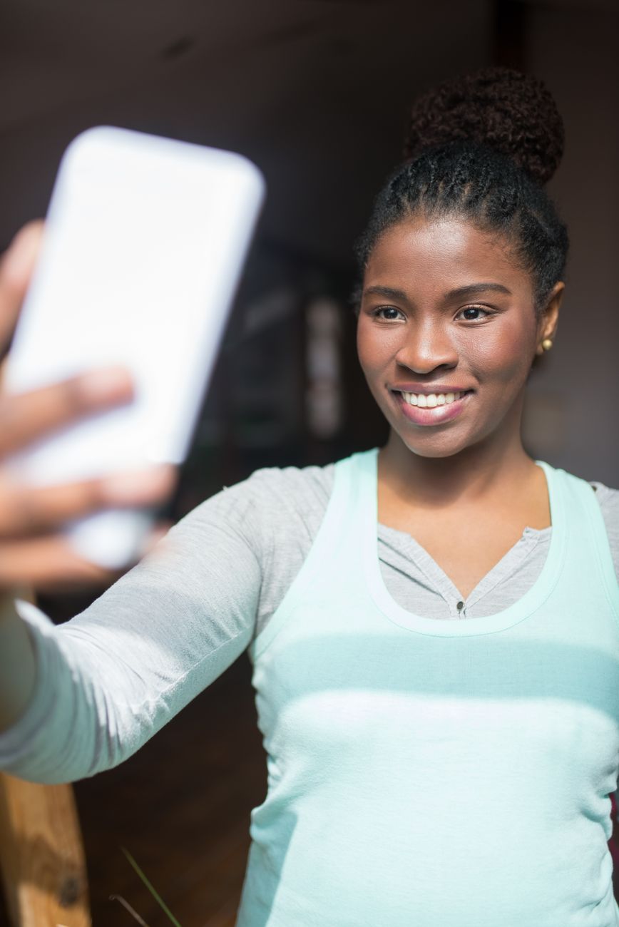 Happy woman taking a selfie indoors, showcasing a joyful expression.