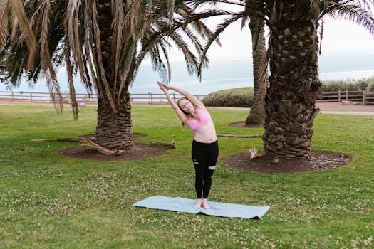 A woman in activewear stretching on a yoga mat outdoors under palm trees.