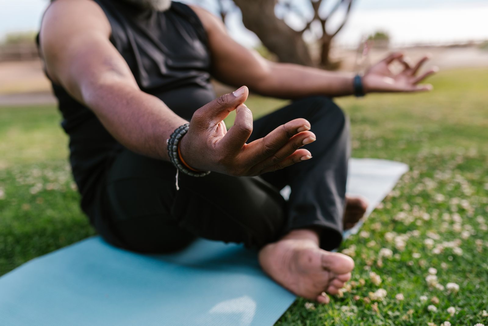 Man practicing a seated lotus meditation pose outdoors on a yoga mat