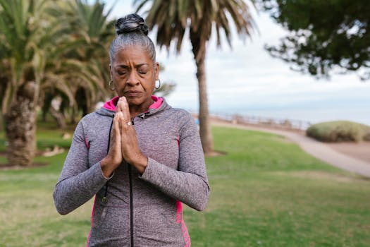 Elderly woman meditating outdoors in a park, promoting health and relaxation.