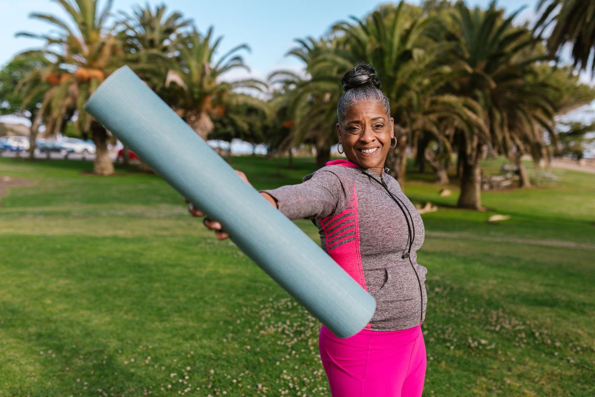 A woman in a sunny park with a yoga mat under her arm — Frances, for BossBabe Gangster (bossbabegangster.com)
