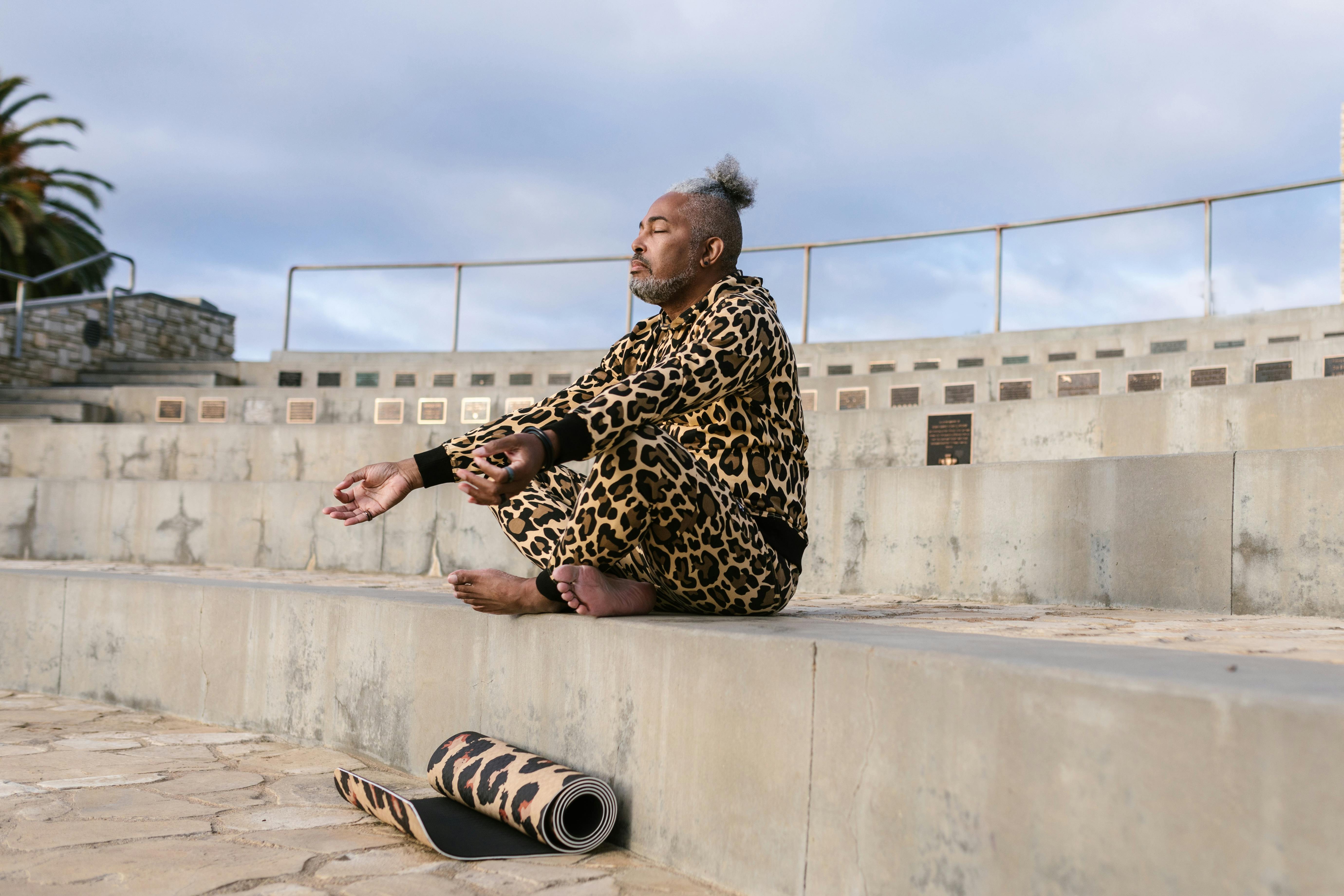Free Man practicing yoga outdoors in an urban amphitheater wearing leopard print attire. Stock Photo