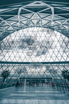 Intricate glass dome design inside Singapore's Jewel Changi Airport with people and symmetry.