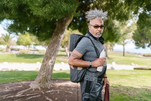 Senior man with backpack and water bottle enjoying a sunny day outdoors.