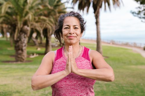 Free Woman practicing yoga in a sunny outdoor park setting, promoting health and balance. Stock Photo
