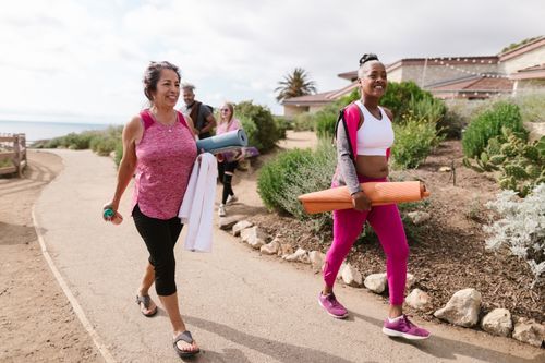 Free Women walking outdoors with yoga mats, enjoying a morning fitness session. Stock Photo
