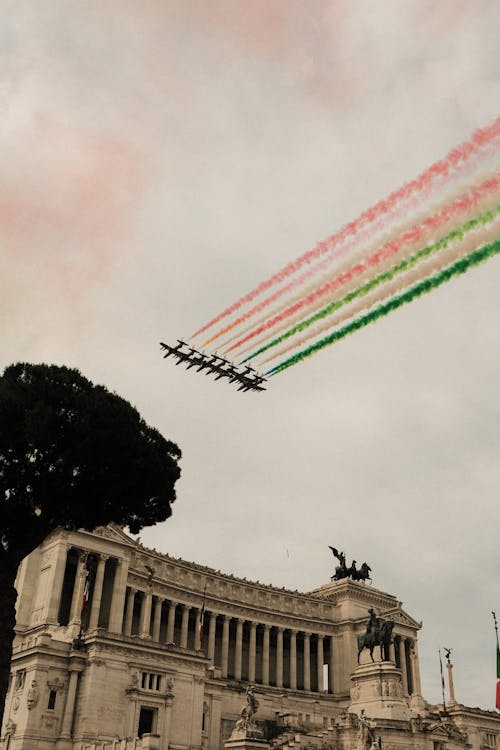 Free Low angle of aircrafts creating air tattoo in cloudy sky over Victor Emmanuel Monument with statues during festive event in Rome Stock Photo
