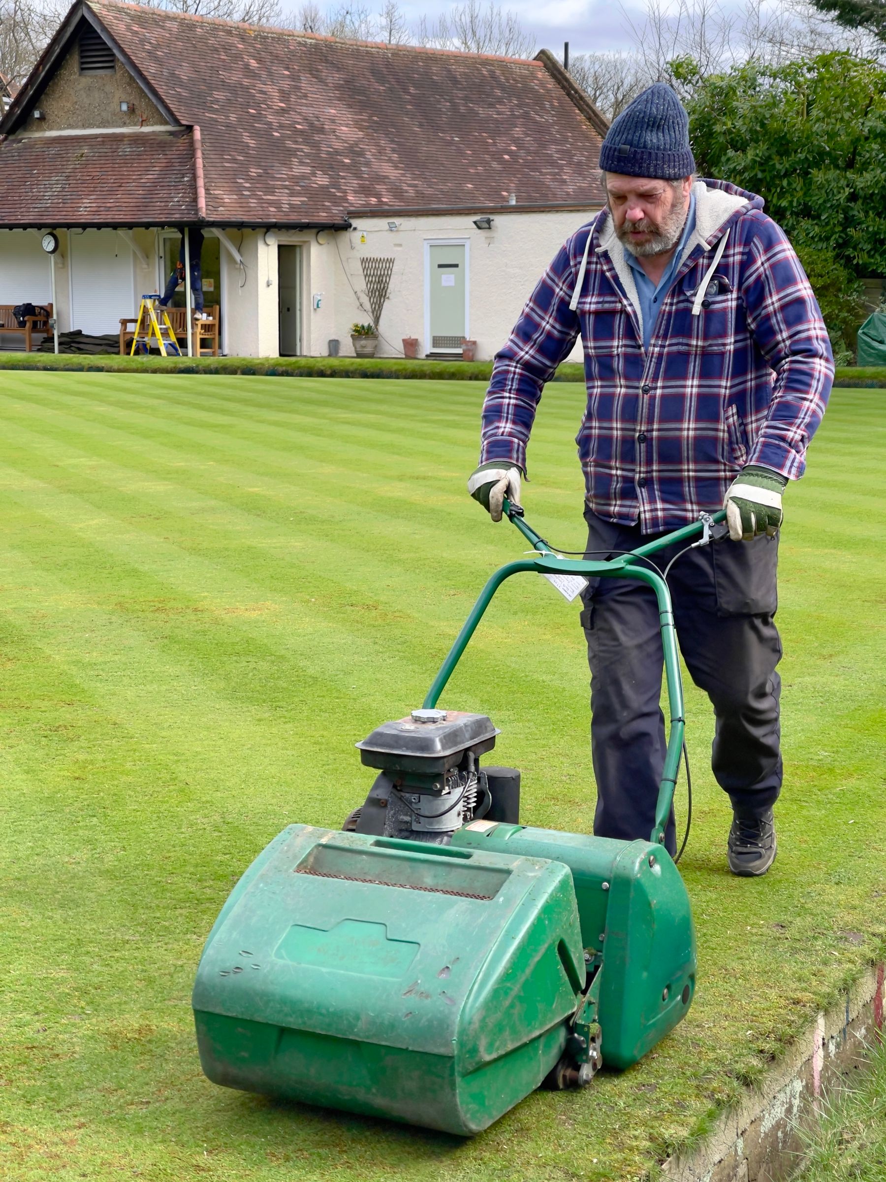 Gardener mowing a lawn in a residential garden