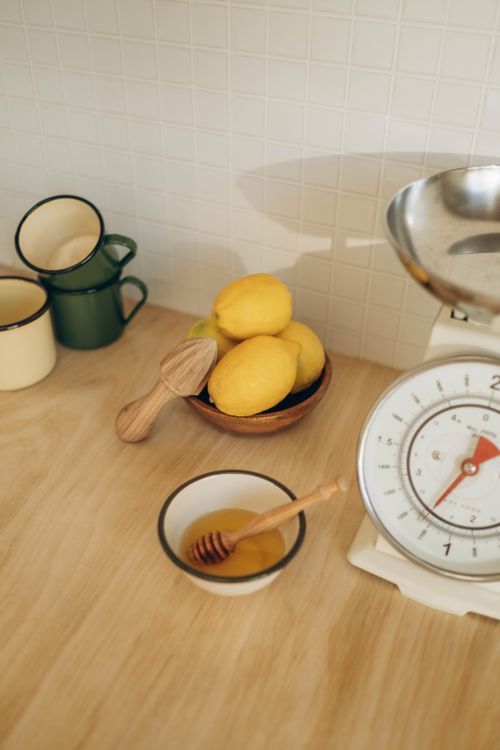 Free Warm kitchen scene featuring lemons, honey, and rustic kitchenware for a homely feel. Stock Photo
