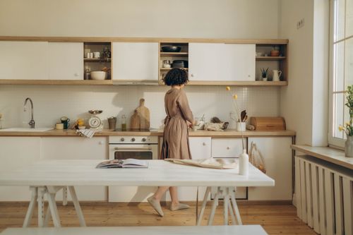 Free A woman casually cooking in a minimalist kitchen with natural light. Stock Photo