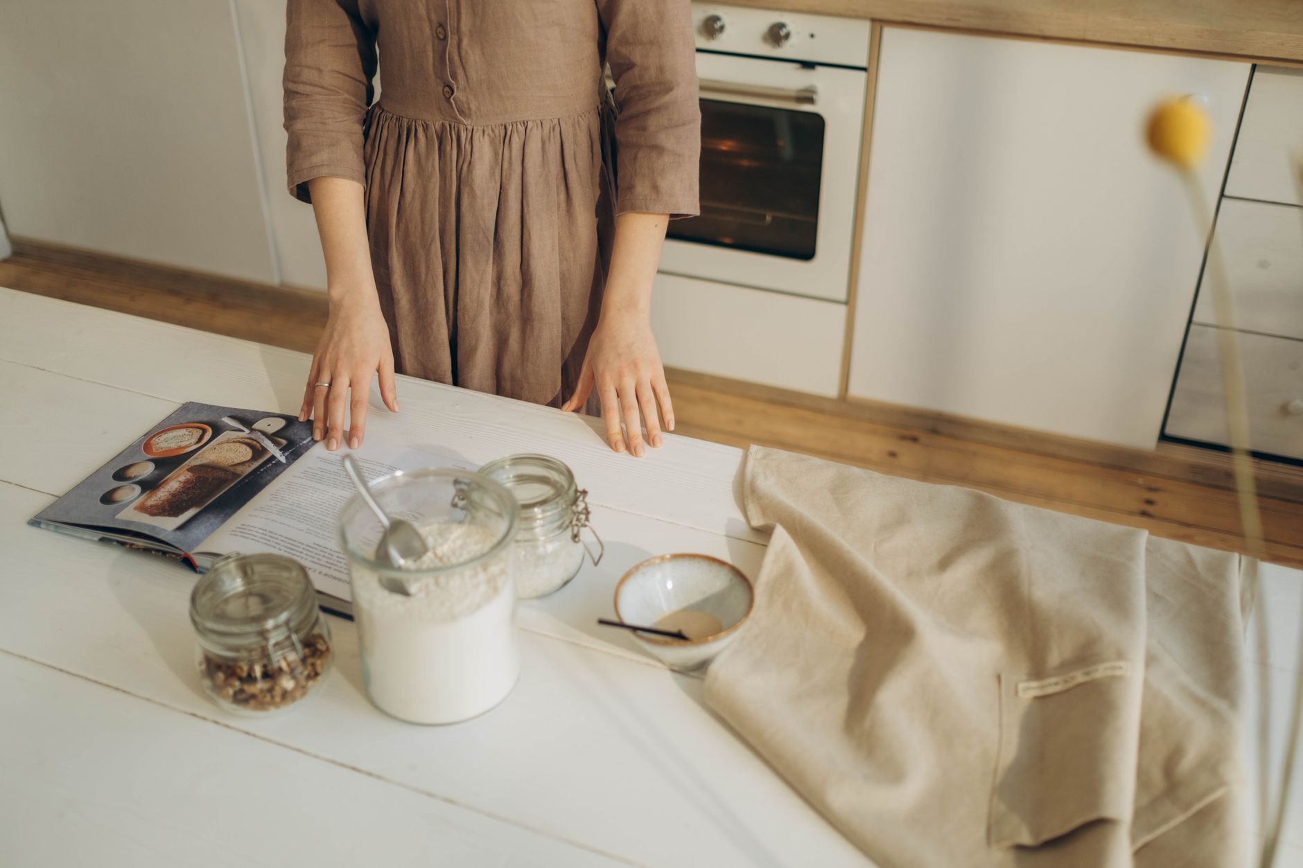 Big News: My Exciting New Cookbook Launch! A person prepares ingredients on a wooden kitchen table with a cookbook for baking.