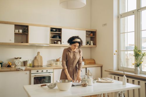 Free A woman with curly hair prepares food in a bright and cozy home kitchen, embracing a peaceful lifestyle. Stock Photo