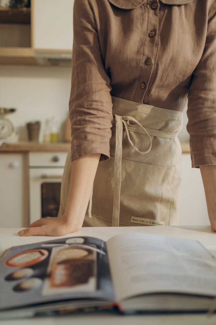 A Close-Up Shot Of A Woman Looking At A Cook Book